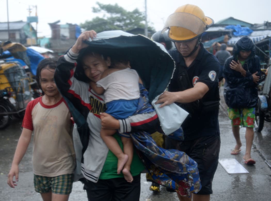 A fireman helps a mother and her family evacuate from their house in Manilla.