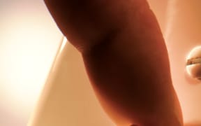 An unseen person turns off a light switch