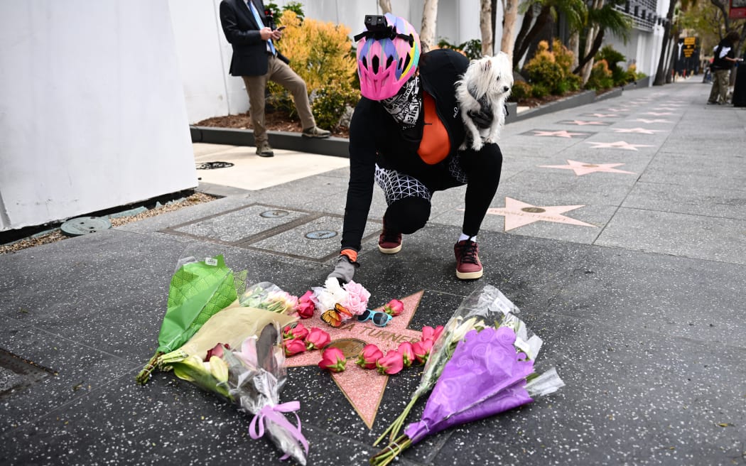 A person places flowers on the Hollywood Walk of Fame star of US-Swiss singer Tina Turner, in Hollywood, California, on May 24, 2023. Rock legend Tina Turner, the growling songstress who electrified audiences from the 1960s and went on to release hit records across five decades, has died at the age of 83, a statement announced on May 24, 2023. (Photo by Patrick T. Fallon / AFP)