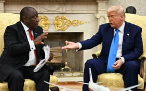 US President Donald Trump hands papers to South African President Cyril Ramaphosa during a meeting in the Oval Office of the White House in Washington, DC, on May 21, 2025. South African President Cyril Ramaphosa meets Donald Trump on Wednesday amid tensions over Washington's resettlement of white Afrikaners that the US president claims are the victims of "genocide."