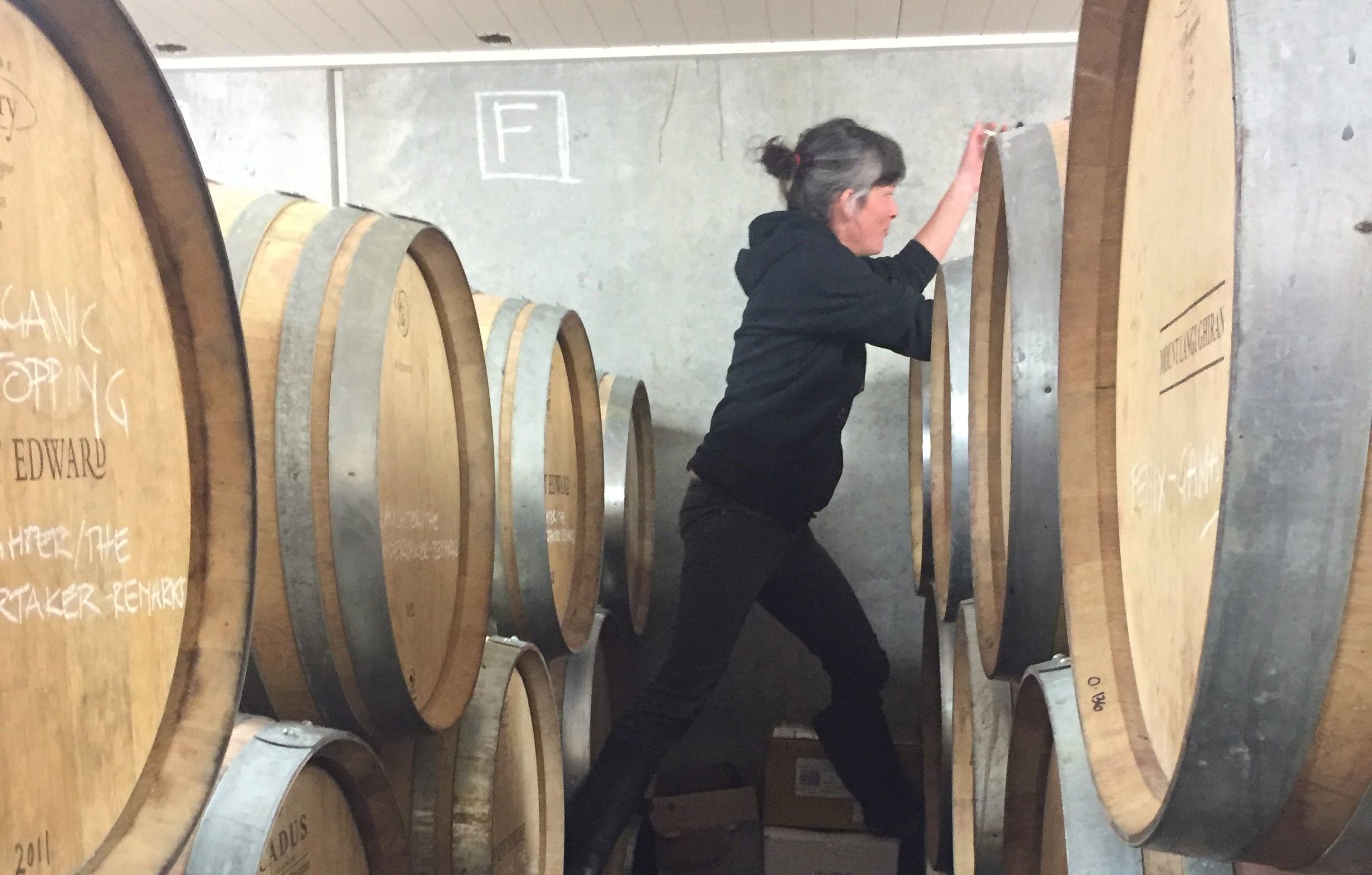 Natural winemaker Anna Riederer scaling barrels to steal a sample of wine for tasting