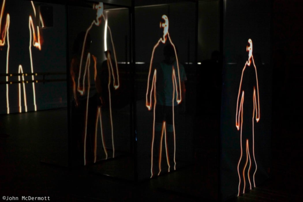 A production still from In Transit showing repeated projected images of human bodies.