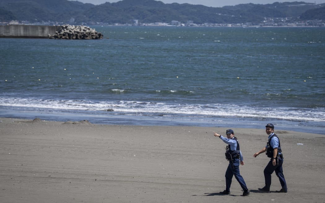 Japanese police officers ask people to evacuate an empty beach due to a tsunami warning in Fujisawa city, Kanagawa prefecture.