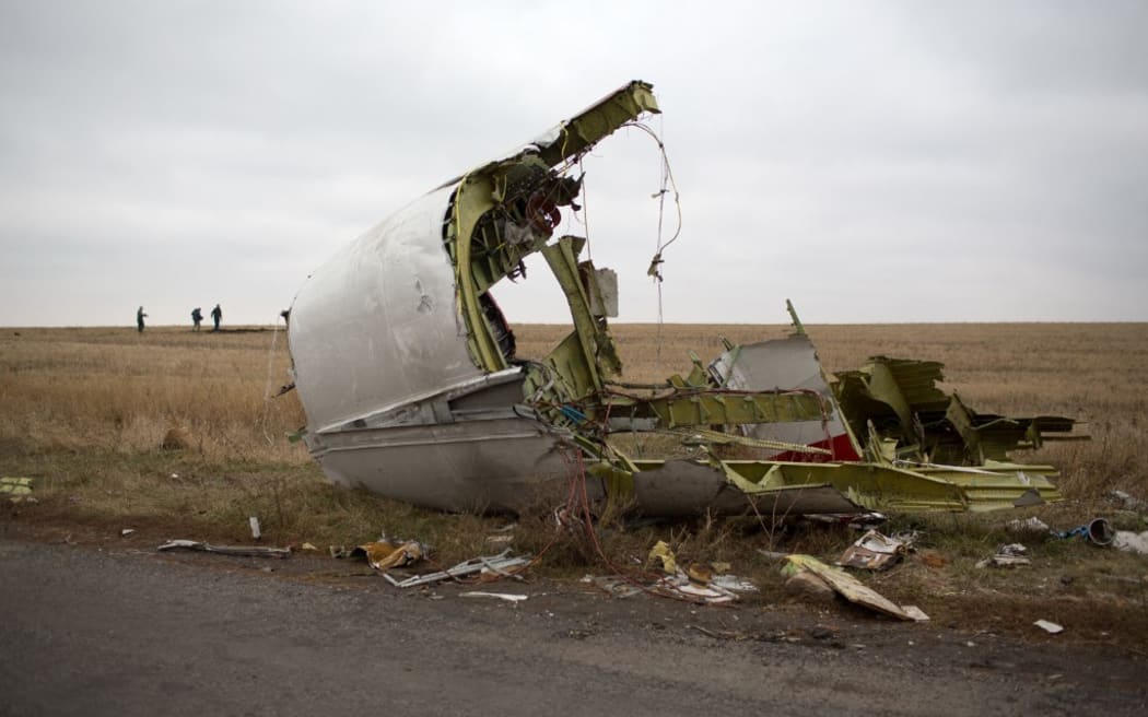 (FILES) In this file photo taken on November 11, 2014 Journalists walk behind parts of the Malaysia Airlines plane Flight MH17 as Dutch investigators (unseen) arrive near at the crash site near the Grabove village in eastern Ukraine, hoping to collect debris from the Malaysia Airlines plane which crashed in July, killing 298 people, in remote rebel-held territory east of Donetsk. - A Dutch court gives its verdict on November 17, 2022 in the trial of four men over the downing of Malaysia Airlines flight MH17 above Ukraine in 2014, as tensions soar over Russia's invasion eight years later. All 298 passengers and crew were killed when the Boeing 777 flying from Amsterdam to Kuala Lumpur was hit over separatist-held eastern Ukraine by what investigators say was a missile supplied by Moscow. (Photo by Menahem KAHANA / AFP)