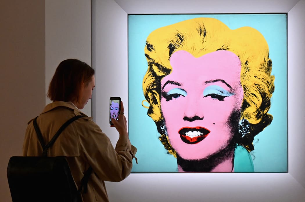 A woman takes a photo of Andy Warhol's 'Shot Sage Blue Marilyn' during Christie's 20th and 21st Century Art press preview at Christie's New York on April 29, 2022 in New York City.