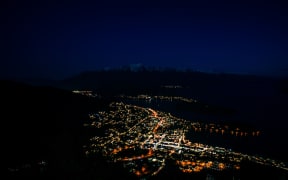 Beautiful night view of Queenstown with the snow capped mountains in the background taken during an orange sunset from the Queenstown, New Zealand Skyline