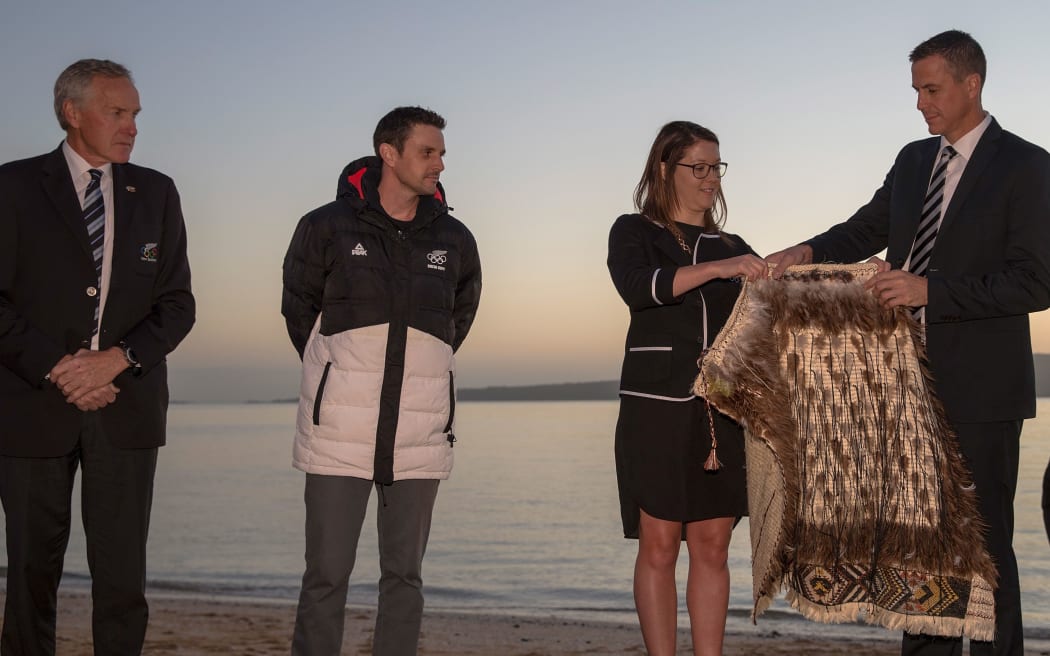 Chef de Mission Rob Waddell is handed the New Zealand Team kakahu (cloak) by Georgina Toomey with Former flagbearer and speed skater Shane Dobbin and Peter Wardell,