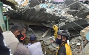 EDITORS NOTE: Graphic content / Rescuers search for survivors at the Mitra Manakarra hospital in Mamuju city on January 15, 2021, where as many as 20 patients and staff are trapped when a 6.2-magnitude earthquake rocked  Sulawesi island.