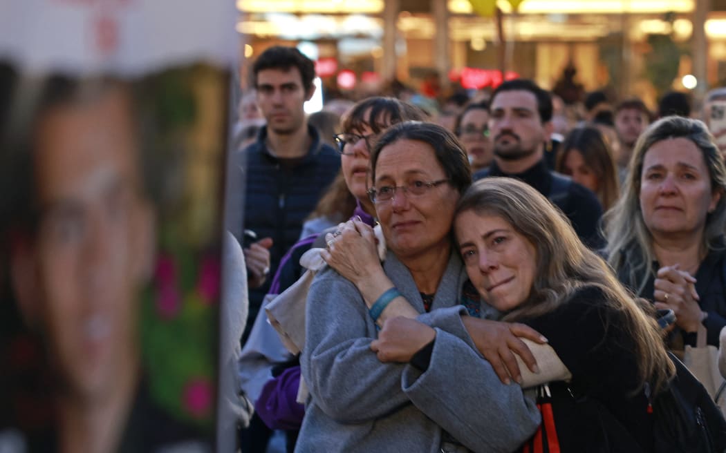 Supporters and relatives of hostages held captive in the Gaza Strip since the October 7, 2023 attacks by Palestinian militants, embrace each other while watching a live television broadcast on the release of Israeli hostages, at the Hostages Square in Tel Aviv, on January 19, 2025. Three women hostages held by militants in the Gaza Strip for more than 15 months are on January 19 to become the first freed under a ceasefire between Israel and Hamas. (Photo by Menahem Kahana / AFP)