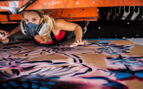 Artist Hayley King, aka Flox, working on a mural in Hamilton