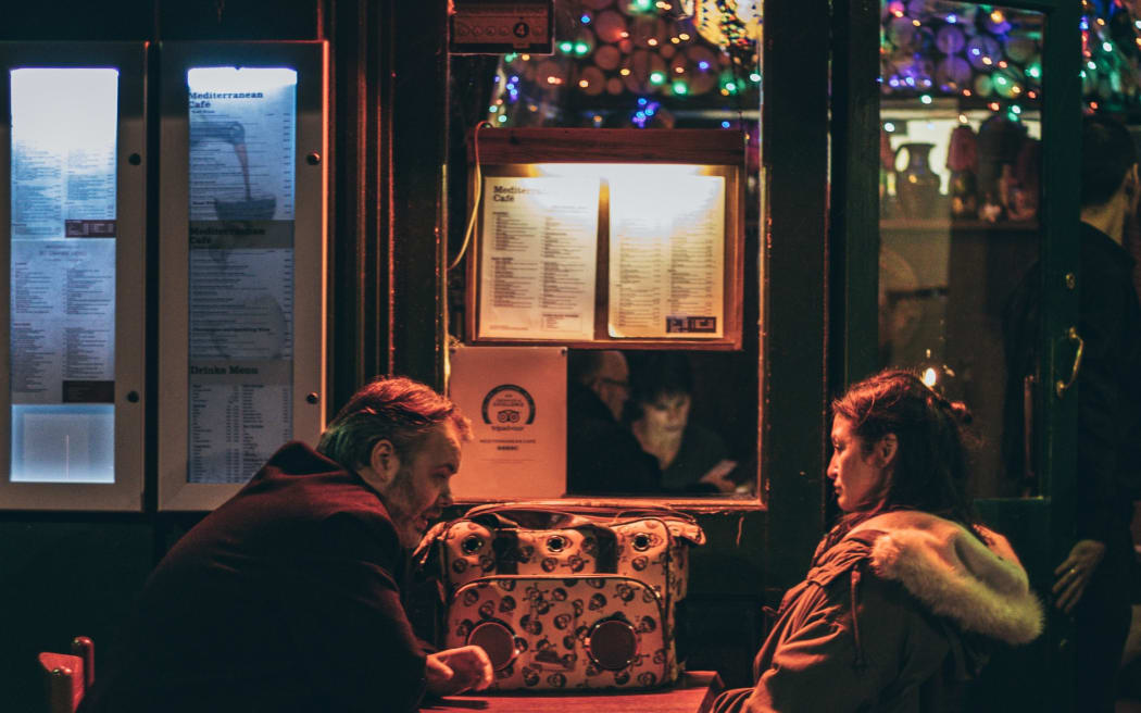 A couple sit in a dark bar