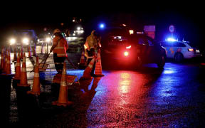 Police cars parked across the road at the scene of a triple fatality in Waiuku, in July 2025.