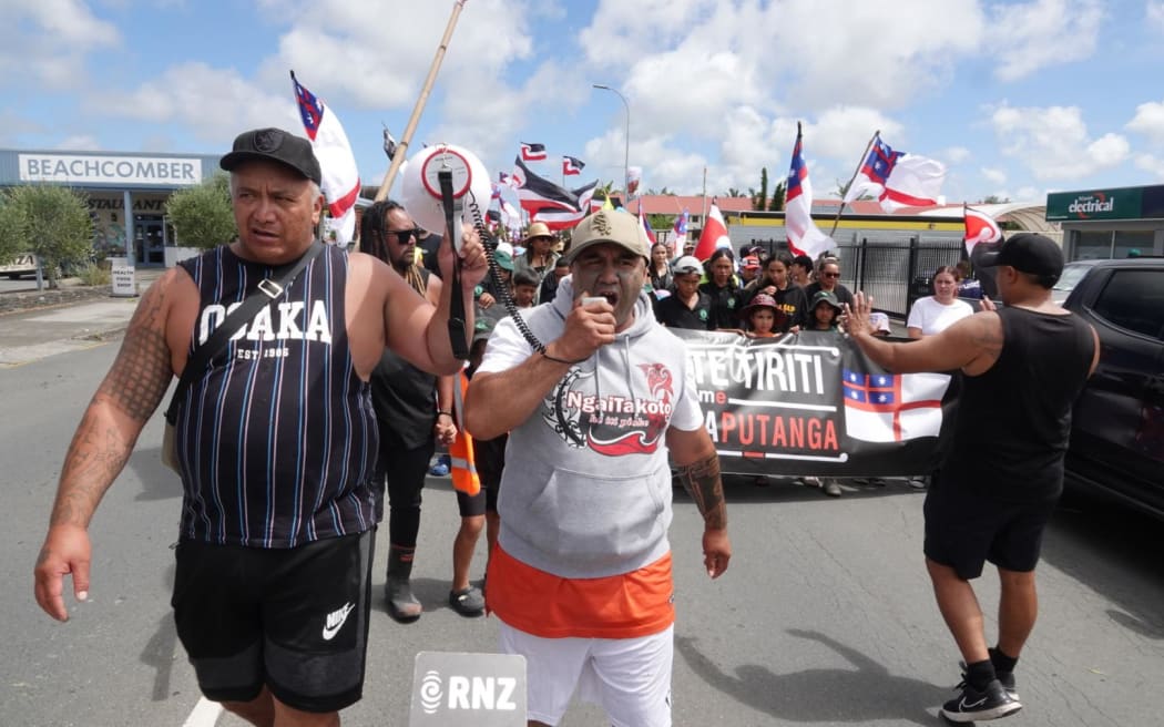 People in the Kaitāia hikoi, including a person speaking into a megaphone and a person holding the megaphone.