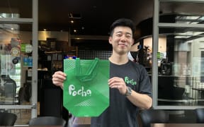 A picture of David Lee, front of house manager at Pocha in Auckland CBD, holding a takeaway bag.
