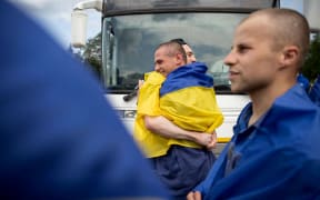 Ukrainian prisoners of war wrapped in Ukrainian national flags hug each other following an exchange at an undisclosed location, amid the Russian invasion in Ukraine.