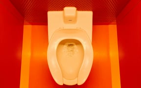 A toilet in a bright bathroom.