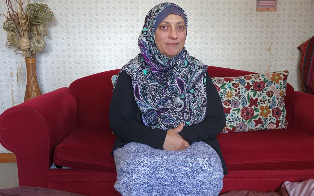 Woman in paisley pattern hijab sits on a red couch