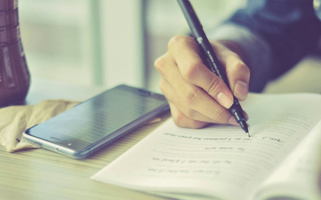 A student writing in an exercise book.
