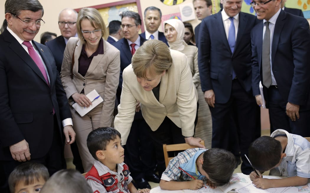 German Chancellor Angela Merkel (C) and Turkish Prime Minister Ahmet Davutoglu (L) talk with refugee children at a preschool, during a visit to a refugee camp on April 23, 2016 on the Turkish-Syrian border in Gaziantep.