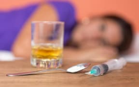 A glass of alcohol and a syringe.