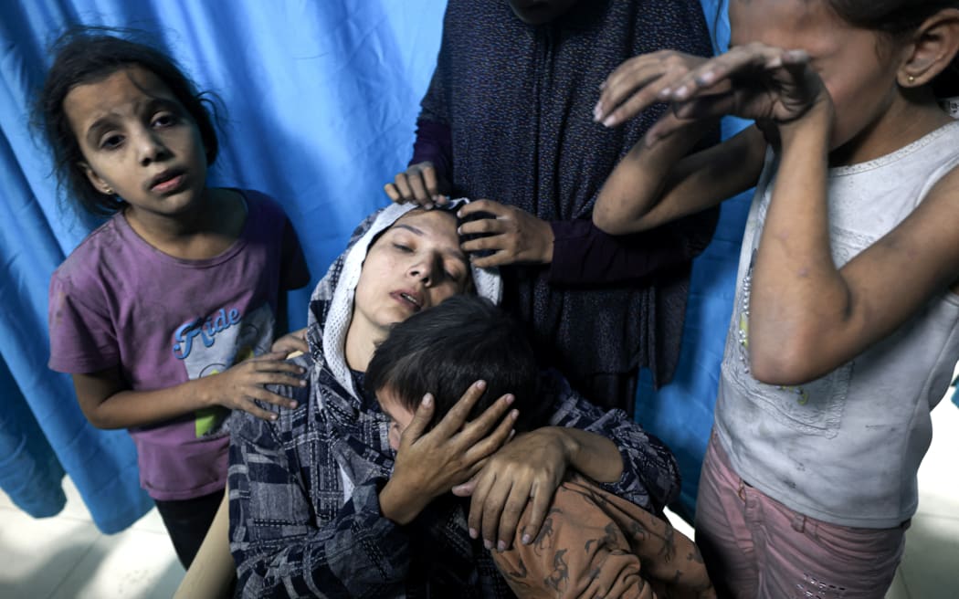 A wounded Palestinian woman from the Baraka family is surrounded by her children upon their arrival at Nasser Hospital in Khan Yunis in the southern Gaza Strip following Israeli air strikes that hit their building on November 13, 2023. Israel is facing intense international pressure to minimise civilian suffering amid a massive air and ground operation that Hamas authorities say has already killed more than 11,000 people, including thousands of children. The military campaign came after Hamas fighters broke through the militarised border with Israel on October 7, killing around 1,200 people, mostly civilians, and taking about 240 people hostage, according to the most recent Israeli figures. (Photo by Mahmud HAMS / AFP)
