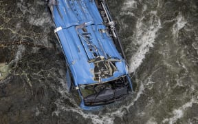 The wreck of a bus lies in the Lerez river after it plunged while crossing a bridge, killing four people, in Cerdedo-Cotobade, northwestern Spain, on December 25, 2022. - The accident occurred on December 24 night near Vigo and the border with Portugal. The regional La Voz de Galicia newspaper said the bus was carrying people visiting their loved ones jailed in Monterroso in central Galicia. Rescue operations had to be suspended overnight due to bad weather but resumed in the morning. (Photo by Brais Lorenzo / AFP)