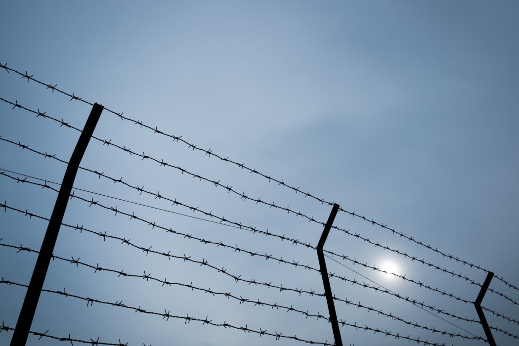 Silhouette of barbed wire on the fence of detention center.