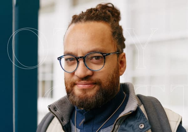 Scotty Cotter has round glasses, pulled back hair and a slight smile.