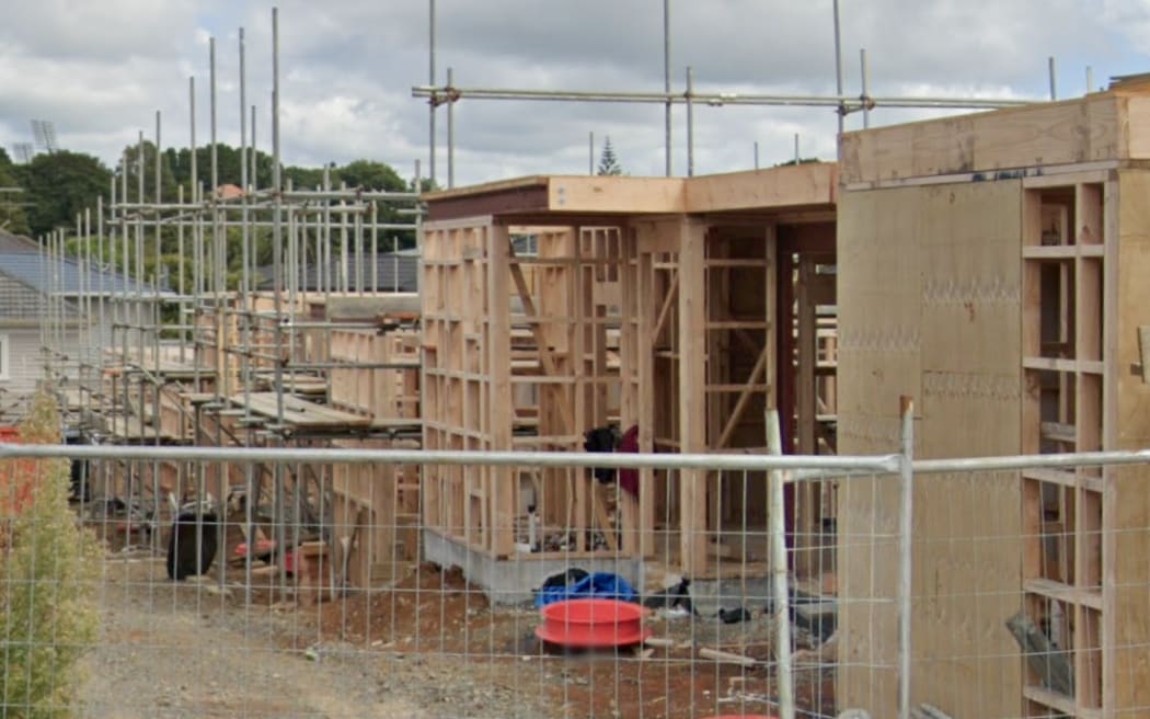 Scaffolding and a fence surround an unfinished construction project of multiple townhouses.