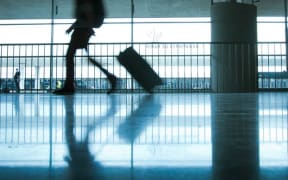 Person at airport with luggage, silhouette.