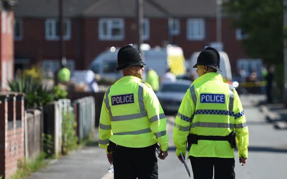 Police officers stand on duty on a cordoned-off road in Fallowfield, Manchester.