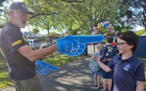 Jeffrey Martin from the New Zealand Police gives a high five welcome to Year Four student Alfonso Chiavone Faccio.