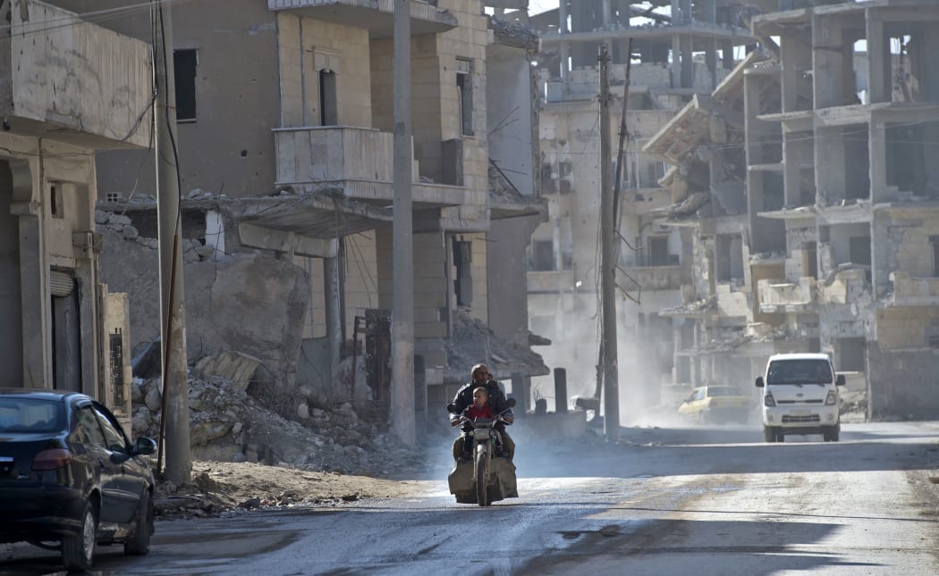A Syrian man and a child ride a motorcycle in the Islamic State (Isis) group's former Syrian capital of Raqqa.