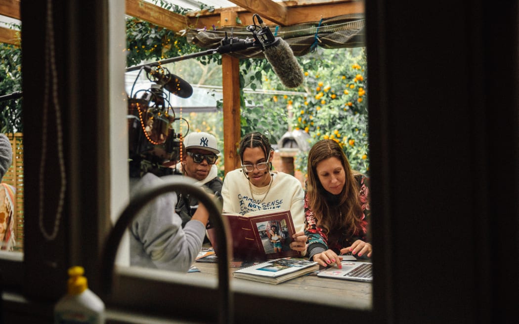 (L-R) Beto, Jamil, and Mara looking at old photo albums while being filmed