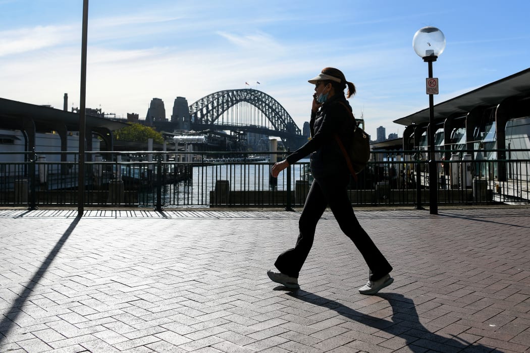 A woman walks along a quiet Circular Quay in Sydney on 6 July 2021, as the city remains in lockdown for a second week to contain an outbreak of the highly contagious Delta Covid-19 variant.