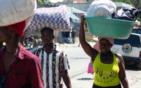 People living near the National Penitentiary, carry their belongings as they leave the area in Port-au-Prince, Haiti, March 4, 2024. At least a dozen people died as gang members attacked the main prison in Haiti's capital, triggering a breakout by several thousand inmates, an AFP reporter and an NGO said on March 3. "We counted many prisoners' bodies," said Pierre Esperance of the National Network for Defense of Human Rights, adding that only around 100 of the National Penitentiary's estimated 3,800 inmates were still inside the facility after the gang assault overnight on March 2. (Photo by Clarens SIFFROY / AFP)
