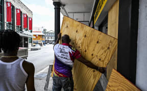 A man prepares to board up a shop window as people prepare for the arrival of Hurricane Beryl in Bridgetown, Barbados on June 30, 2024.