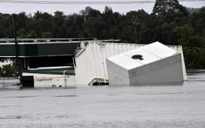 A container floats as rising floodwater inundated a commercial area during heavy rain in southwestern Sydney suburb of Camden on 8 March, 2022.