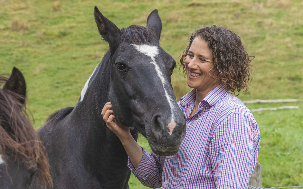 Storm Baynes-Ryan smiling and stroking a black horse
