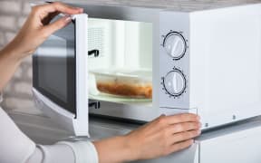 Woman's Hands Closing Microwave Oven Door And Preparing Food At Home