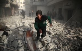 A Syrians youth runs following an air strike in the rebel-held enclave of Arbin in the Eastern Ghouta near Damascus on February 8, 2018.