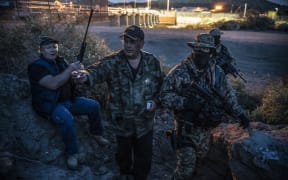 (FILES) In this file photo taken on March 20, 2019 Jeff Allen, Jim Benvie, Viper and Stinger share cigarettes while patrolling the US-Mexico border in Sunland Park, New Mexico on March 20, 2019.