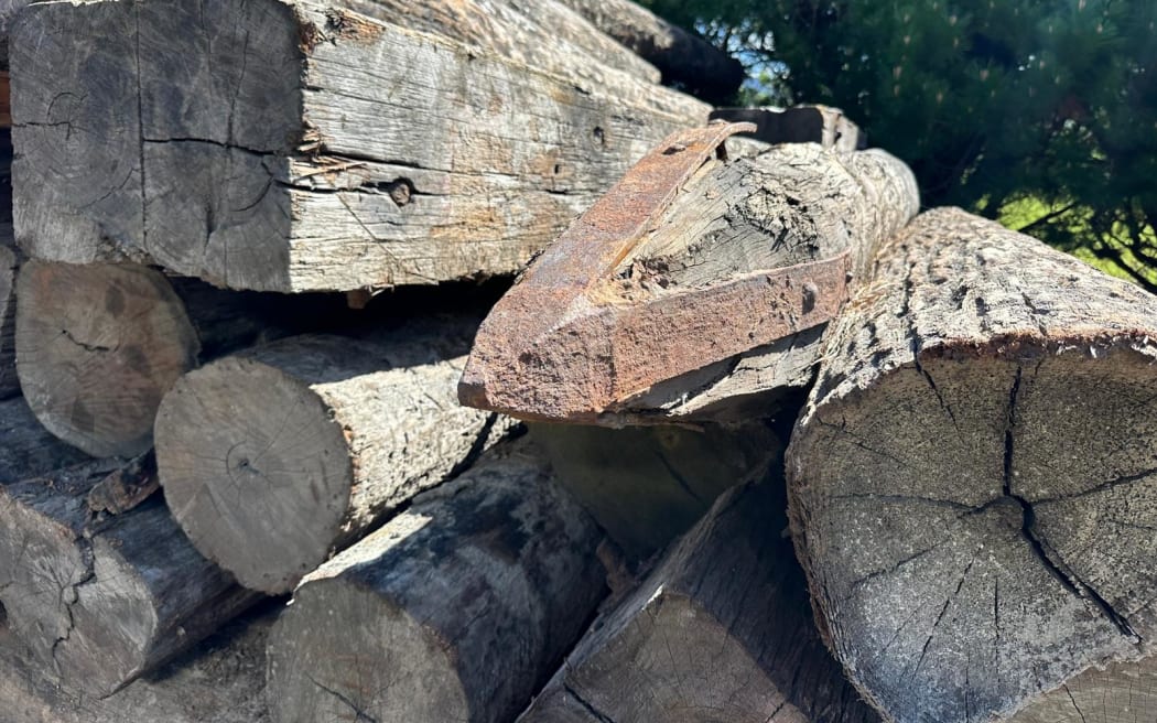 A close-up of recycled ironbark timber piles and beams lying in a pile, some still showing the steel and nails used in the building process