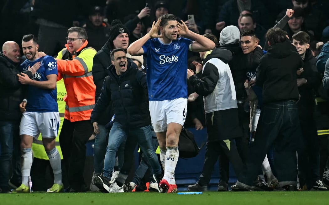 Everton captain James Tarkowski is mobbed by fans as he celebrates scoring the equaliser against Liverpool.