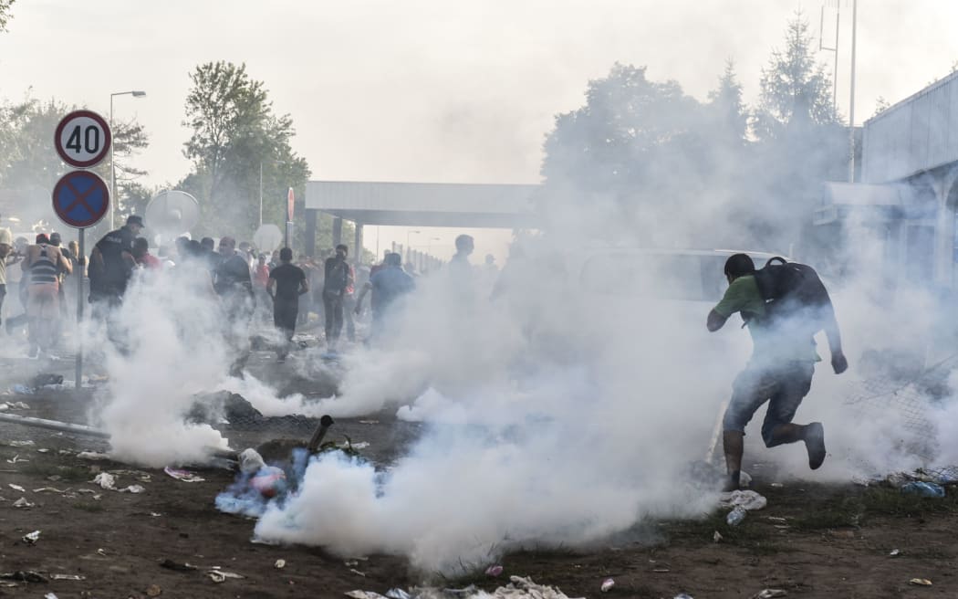 Migrants run away from tear gas thrown by Hungarian anti-riot police officers at the Hungarian border with Serbia near the town of Horgos.