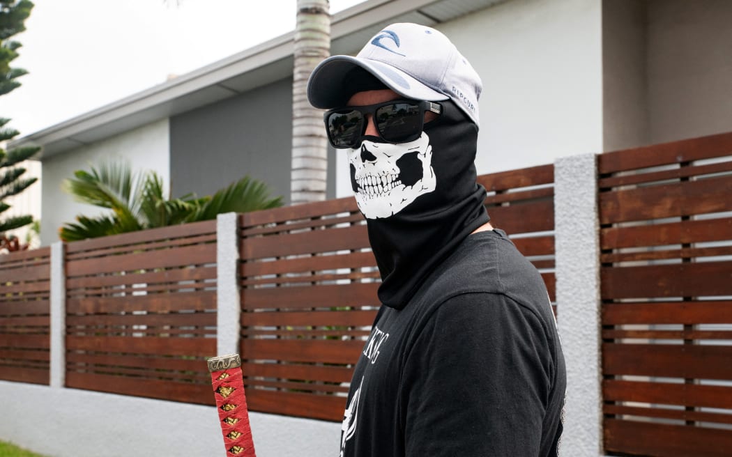 A masked resident of neighborhoods south of the capital, stands near a roadblock set-up to block access and channel pro-independence activists at the entrance to Tuband, in the Motor Pool district of Noumea on May 15, 2024, amid protests linked to a debate on a constitutional bill aimed at enlarging the electorate for upcoming elections of the overseas French territory of New Caledonia. One person was killed, hundreds more were injured, shops were looted and public buildings torched during a second night of rioting in New Caledonia, authorities said Wednesday, as anger over constitutional reforms from Paris boiled over. (Photo by Delphine Mayeur / AFP)