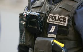 A photograph shows a police body-worn camera, attached on the clothing of a French police officer standing guard during a visit of French Minister of Education, Sports, and Olympic Games outside the Littre public school in Paris on January 16, 2024. Amelie Oudea-Castera, at the heart of a controversy surrounding the schooling of her children, visits the Littre public school on January 16, 2024 - from which she withdrew her eldest son to put him in private school - in the hope of putting an end to the Attal government's first crisis.