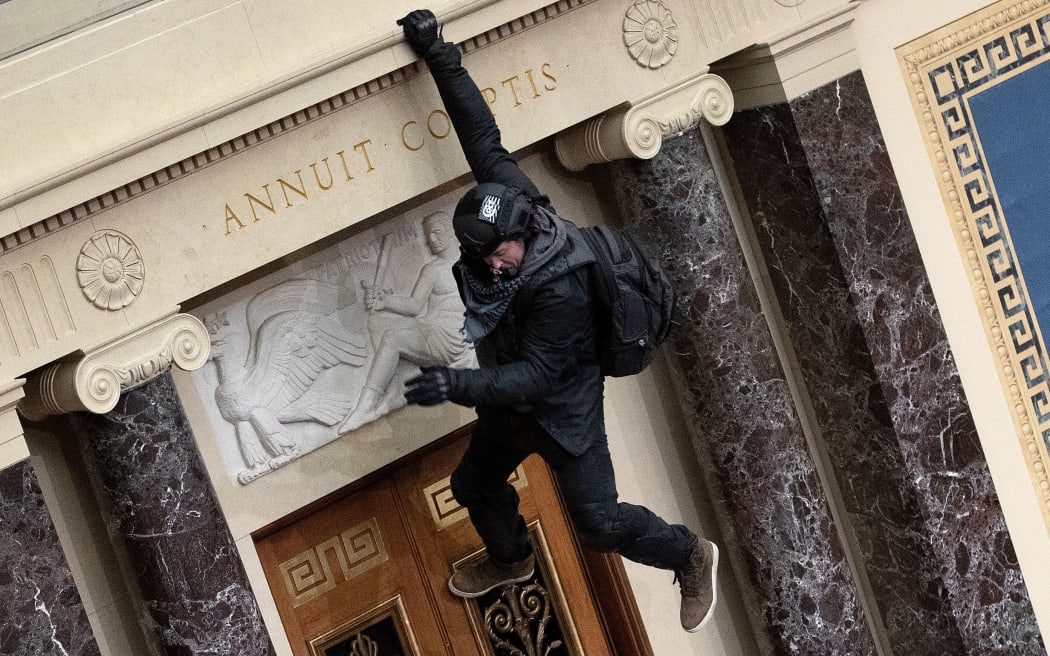 A protester supporting US President Donald Trump jumps from the public gallery to the floor of the Senate chamber at the U.S. Capitol Building on January 06, 2021 in Washington, DC.