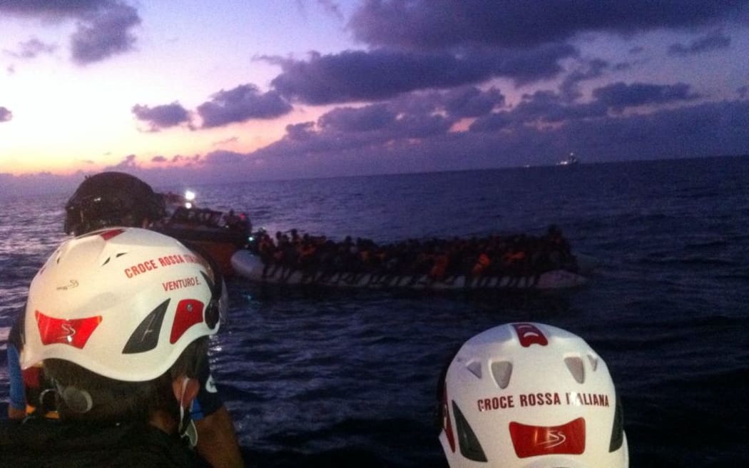 Red Cross workers spot more than 100 people on a flimsy dinghy, leaking oil.