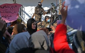 Taliban fighters stand guard on a vehicle as Afghan women protest at Shahr-e Naw in Kabul on December 16, demanding the right to education, jobs and political representation from the Taliban government.
